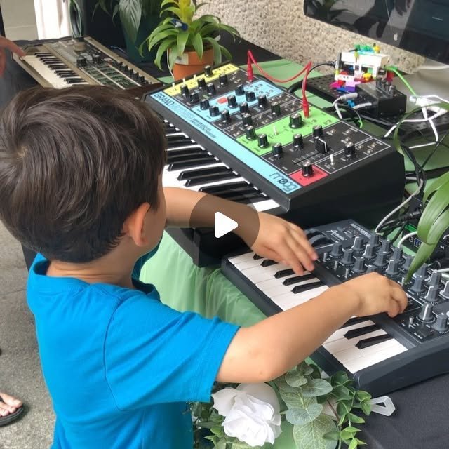 A child plays a synthesizer keyboard surrounded by potted plants wired with clip-on sensors and cables.